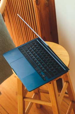 İnce bir dizüstü bilgisayar iç kısımda şık bir sandalyede duruyor..