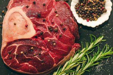 Taze et. Kemik ossobuco 'sunda büyük bir biftek. Siyah arka planda bir filiz biberiye..