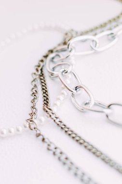 Beyaz estetik arka planda takı zincirleri olan beyaz boncuklu bir kolye..