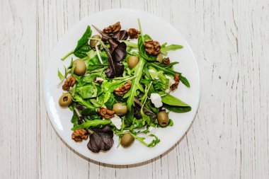 Salata yaprakları roka, peynir, yeşil zeytin ve fındık tabakta, sağlıklı diyet salatası..