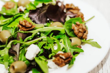 Salata yaprakları roka, peynir, yeşil zeytin ve fındık tabakta, sağlıklı diyet salatası..