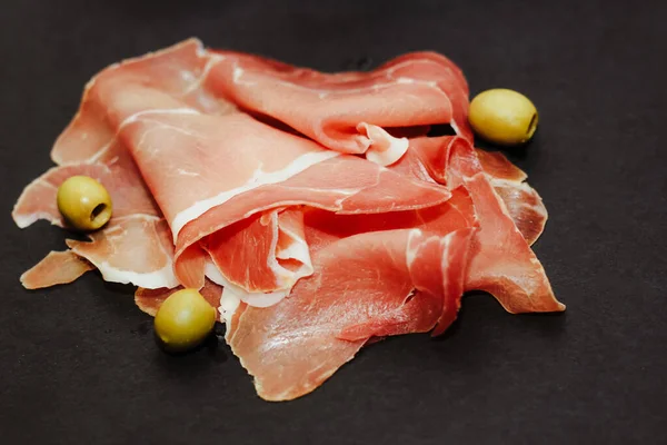 黒ボード上のオリーブと乾燥豚肉のジャモンプロシクトの作品 — ストック写真