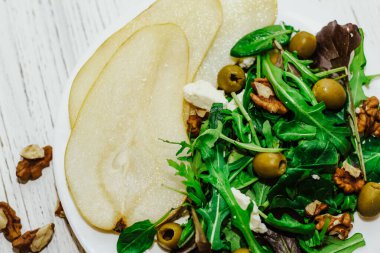 Armutlu salata, otlar, roka, prosciutto, peynir, yeşil zeytin ve fındık..