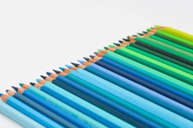 Çok renkli kalemler beyaz bir masada, yeşil renk aralığında uzanır..