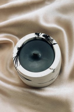 Dekoratif bir alçı şamdanla ipek bir çarşafın arka planında mumla