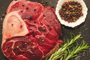 Taze et. Kemik ossobuco 'sunda büyük bir biftek. Siyah arka planda bir filiz biberiye..