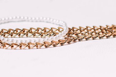 Beyaz estetik arka planda takı zincirleri olan beyaz boncuklu bir kolye..