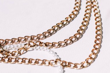 Beyaz estetik arka planda takı zincirleri olan beyaz boncuklu bir kolye..