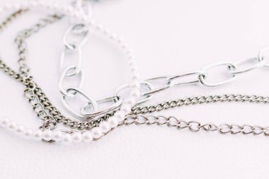 Beyaz estetik arka planda takı zincirleri olan beyaz boncuklu bir kolye..