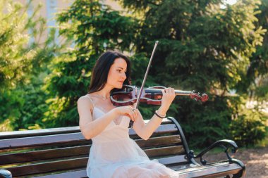 Siyah saçlı, tahta konser kemanı çalan bir kadın sanatçı.