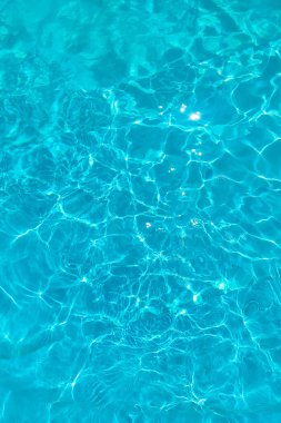 Mavi bir havuzda, güneşten yansıyan mavi saydam su dokusu.