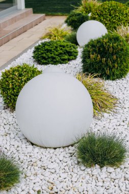 Kostrytsia Gauthier bahçe arka planda beyaz dekoratif taşlar ve yuvarlak bir bahçe lambası