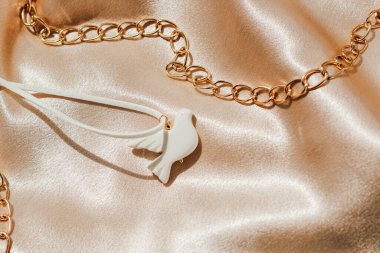 ipek kumaşın arka planında polimer kilden yapılmış bijouterie beyaz kuş.