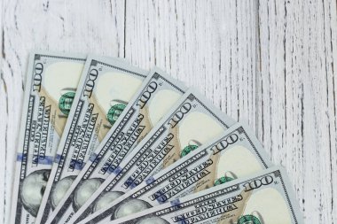 Tahta arka planda 100 dolarlık faturalar.
