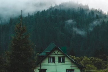 Dağ sisli ormanlarında ahşap bir ev, dağ manzarası.