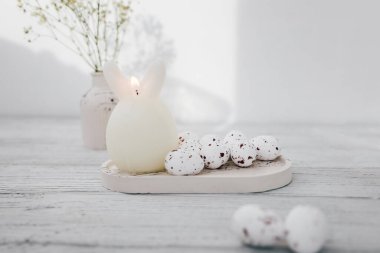 Yumuşak pastel Paskalya dekorasyonu. Basit bir masada bahar düzenlemesi ve dekoratif yumurtalar var.