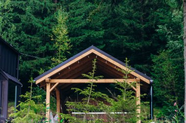 Uzun ağaçların arasında duran büyüleyici bir ahşap pavyon dinlenmek ve toplanmak için mükemmel huzurlu bir atmosfer yaratıyor..