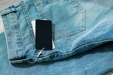 Denim kotu yumuşak doğal ışık tarafından aydınlatılan kırsal ahşap bir yüzeyde gelişigüzel duran fiyat etiketleriyle şık bir tasarıma sahiptir..