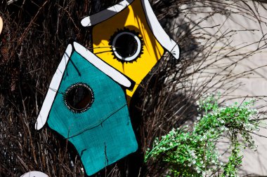 Birbirine dolanmış dalların arasında asılı iki parlak kuş evi bahçe düzenine cazibe ve renk katıyor. Yeşillik kırsal cazibeyi artırarak gözetliyor.