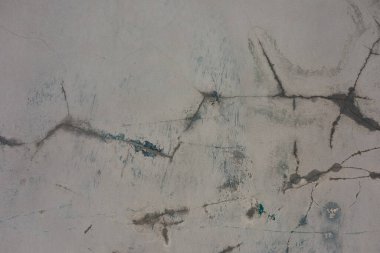 Doğal ışık altındaki bir şehir ortamında çatlakları ve renk parçalarını gösteren eski bir beton yüzeyin yakın görüntüsü.