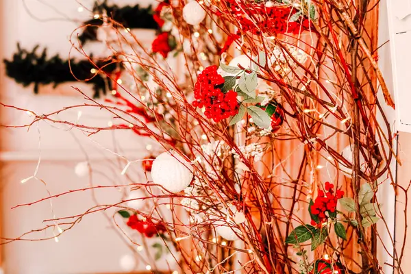 Parlak kırmızı çiçekler ve beyaz süslemeler ince dallar ve sicim ışıklarıyla iç içe geçerek tatil toplantıları için mükemmel bir şenlik ortamı yaratıyor..