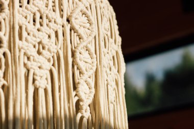 Detaylı makrome duvar iç mekan işçiliği ve doğal ışıkta estetik cazibeyi gösteren dokuma desenli asılı..