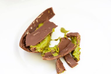 Dubai Çikolatalı Pistachio Kataifi parlak yeşil dolgu büyüleyici bir kontrast oluşturuyor. Tatlı temiz beyaz bir tabağa konur..