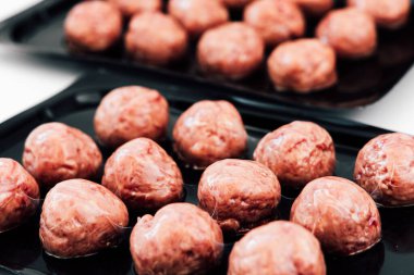 Pişmemiş köftelerle dolu tabaklar, öğlen vakti yerel bir gıda pazarında sergileniyor ve onların dokusunu ve tazeliğini ön plana çıkarıyor..