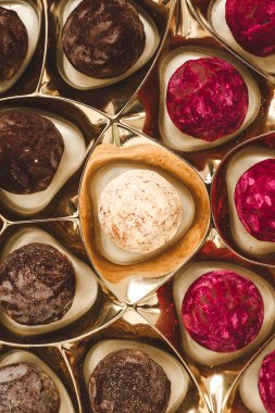 Çeşitli aromalı lezzetli çikolatalı trüf mantarları, canlı renkler ve zengin dokular sergilenen altın bir kutuda ustaca düzenlenmiştir..