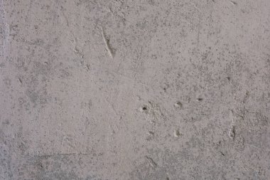 Kaba dokuyu ve doğal ışık kusurlarını vurgulayan ince renk değişikliklerini gösteren beton bir duvarın yakın görüntüsü.