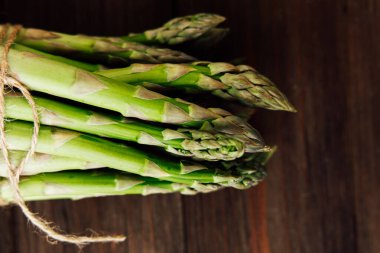 Kırsal bir ahşap masada sicimle korunan bir avuç taze yeşil kuşkonmaz. Sağlıklı yemek seçenekleri için mükemmel..