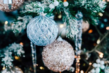 Gümüş ve altın aksanlı Noel ağacından sarkan dekoratif süsler bayramlar için şenlikli bir ortam yaratıyor..