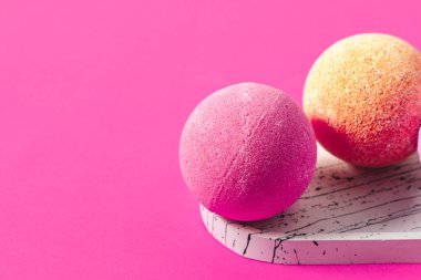 Parlak pembe ve turuncu banyo bombaları şık bir mermer tepsiye yerleştirilir ve renkleri ve dokuları renklendirilir..