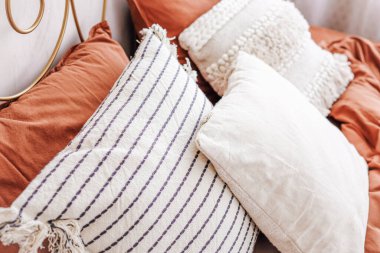 Yumuşak dekoratif yastıklar çeşitli dokularda ve desenlerde, rahat bir atmosfer yaratacak şekilde sıcak bir yatak ile düzgünce yapılmış bir yatağa yerleştirilir..