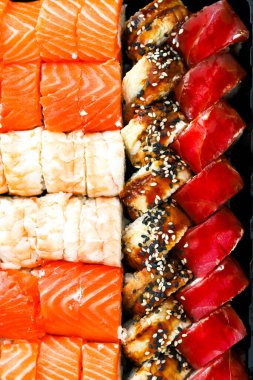 Canlı bir suşi çeşidi siyah bir tepside güzelce düzenlenmiştir..