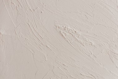 Yüzey, zarif akış çizgileri ve sanatsal bir etki yaratan küçük kusurları içeren desenli beyaz bir duvar sergiliyor..