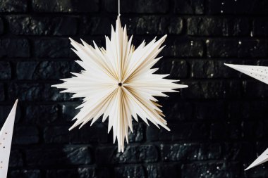 Göz kamaştırıcı beyaz bir yıldız, koyu tuğladan bir duvara karşı zarafetle asılıp şenlikli atmosfere cazibe katar..