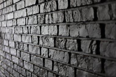 Koyu renkli bir tuğla duvarın yakından bakınca tuğla ve harç ile oluşturulan çeşitli doku ve desenler sergileniyor..