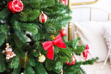 Güzel dekore edilmiş bir Noel ağacında kırmızı fiyonklar ve parlak süsler rahat bir oturma odasında şenlikli bir atmosfer yaratıyor..