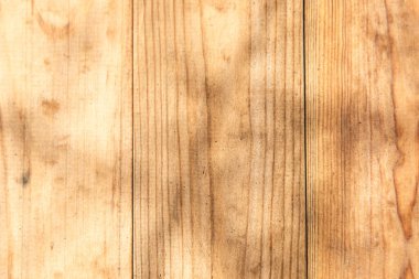 Doğal ahşap yüzey, kalaslarda görünen eşsiz tahıl ve dokuya vurgu yapan güneş ışığının oluşturduğu gölgelerle detaylı bir örüntü gösteriyor..