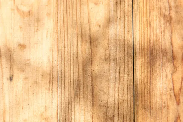 Doğal ahşap yüzey, kalaslarda görünen eşsiz tahıl ve dokuya vurgu yapan güneş ışığının oluşturduğu gölgelerle detaylı bir örüntü gösteriyor..