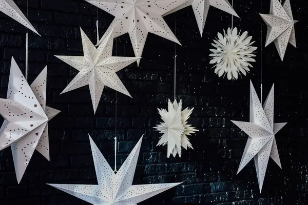 Hassas beyaz kağıt yıldızlar ve kar taneleri tavandan sarkan koyu tuğla bir duvara asılı. Odadaki neşeli atmosferi güçlendiriyor..