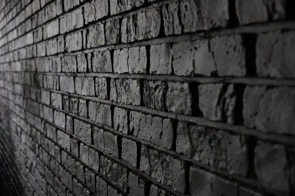 Koyu renkli tuğla bir duvara yakından bakınca kaba dokusu ve benzersiz desenleri ortaya çıkıyor. Bu da kentsel ortamlarda tipik bir endüstriyel hissi uyandırıyor..