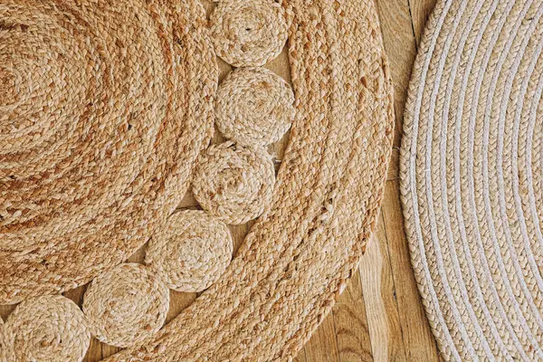 İki farklı doğal dokuma halı ahşap bir zeminde duruyor. Karmaşık tasarımlar ve dokular sergileniyor..