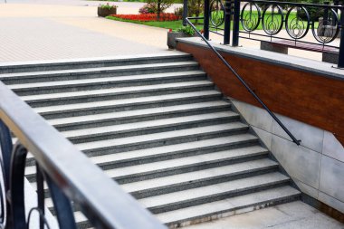 Bir dizi beton merdiven ziyaretçileri dekoratif bir geçitten zengin bir bahçe alanına indiriyor ve kent parklarının güzelliğini vurguluyor..