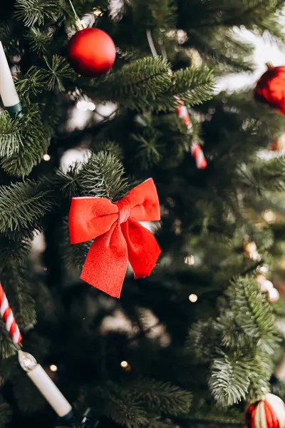 Şenlikli bir Noel ağacında canlı kırmızı bir fiyonk bulunur. Etrafı süslerle çevrilidir. Neşeli bir tatil ortamı yaratır..