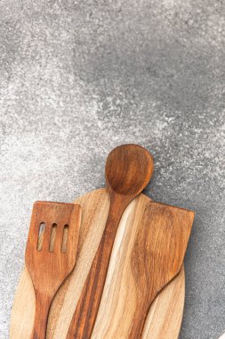 Çeşitli ahşap pişirme aletleri, yemek hazırlamak ve servis etmek için ideal gri bir yüzeye düzgün bir şekilde yerleştirilmiştir..