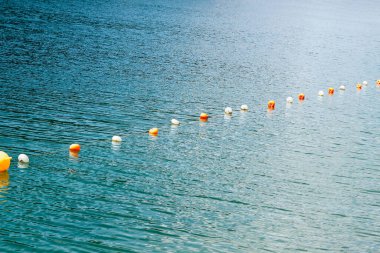 Renkli şamandıralar gün boyunca gölün sakin sularını kaplıyor. Açık hava aktiviteleri için canlı bir atmosfer yaratıyor..