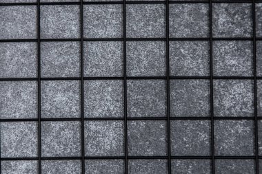 Gri desenli kiremitler şebeke şeklinde dizilmiş. Kapalı bir duvarda parlak ve çağdaş bir görünüm yaratıyor. Tasarım görsel ilgi ekliyor.