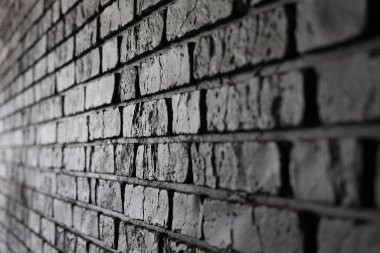 Işığın oluşturduğu dokuyu ve gölgeleri vurgulayan siyah tuğla bir duvarın yakın plan görüntüsü.